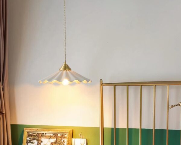 Suspension céramique ondulation élégante, de couleur blanche, suspendue et allumée. Fond beige et vert.