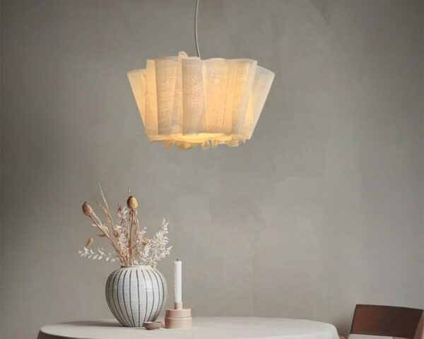 Suspension lin design artistique vintage, allumée, suspendue au-dessus d'une table avec un vase dessus. Fond clair.