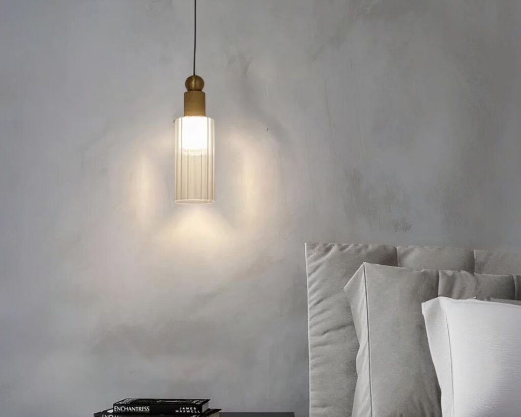Petite suspension en cuivre au design moderne sur fond gris.