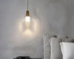 Petite suspension en cuivre au design moderne sur fond gris.