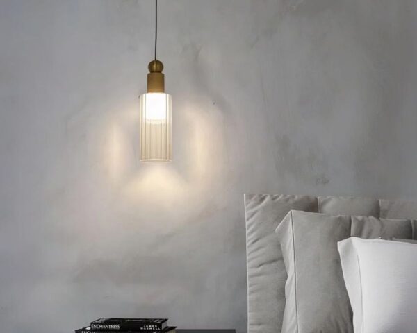 Petite suspension en cuivre au design moderne sur fond gris.