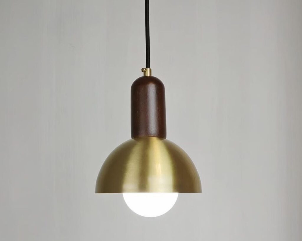 Petite suspension en cuivre de style champignon sur fond gris.