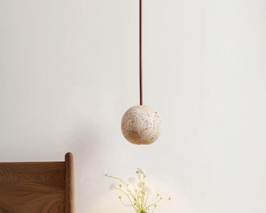 Petite suspension design en pierre de travertin sur fond gris.