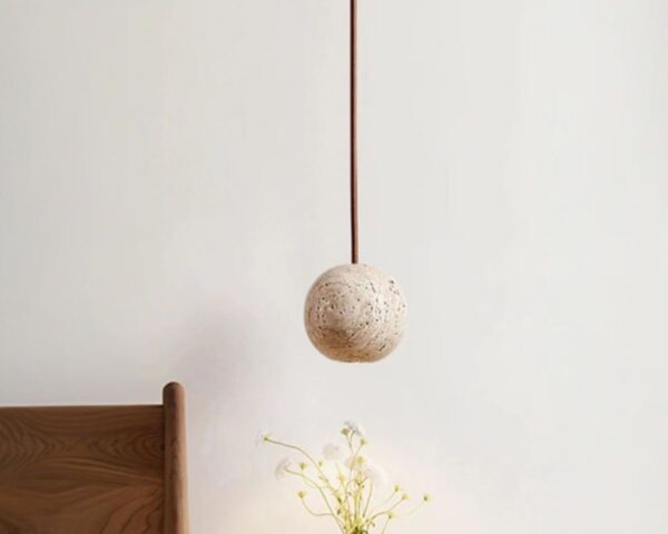 Petite suspension design en pierre de travertin sur fond gris.