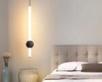 Petite suspension minimaliste et moderne dans une chambre avec un lit sur la droite.