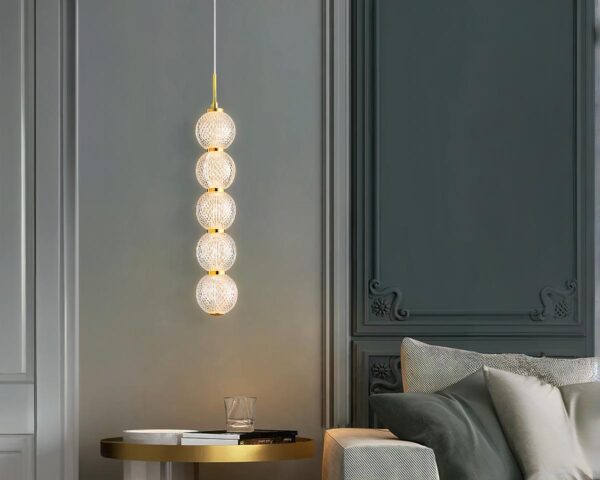 Suspension ampoule dorée et chic au style luxueux allumée dans un salon