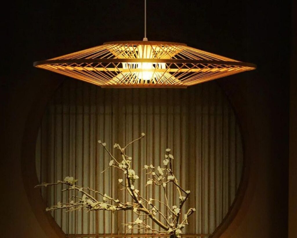 Suspension bambou moderne et élégante allumée dans une pièce avec un bonsaï en dessous.
