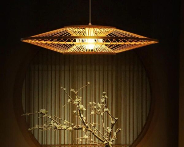 Suspension bambou moderne et élégante allumée dans une pièce avec un bonsaï en dessous.