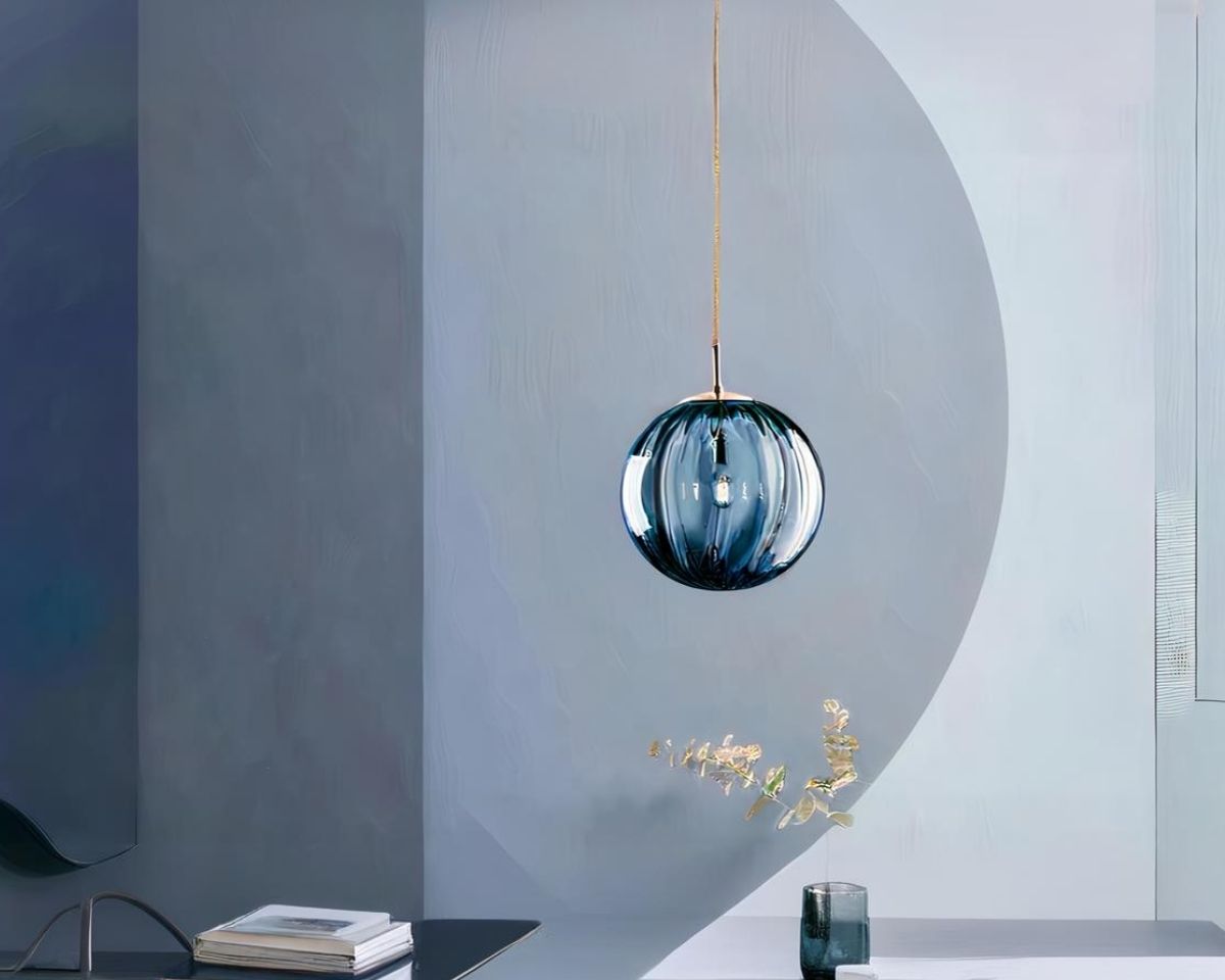 Suspension boule moderne au style nordique en verre bleue allumée dans un salon aux murs bleus et gris.