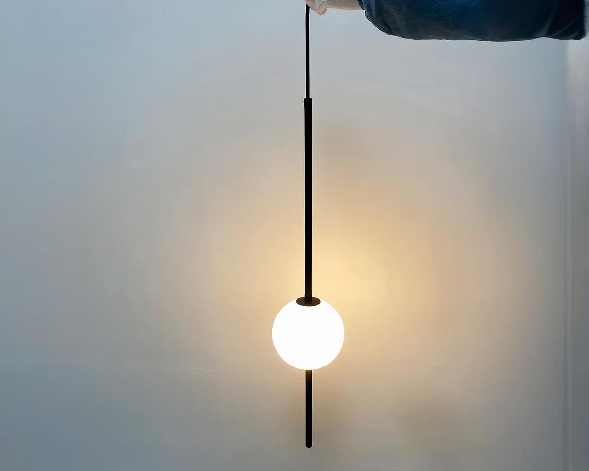 Suspension chambre minimaliste avec boule en verre sur fond gris