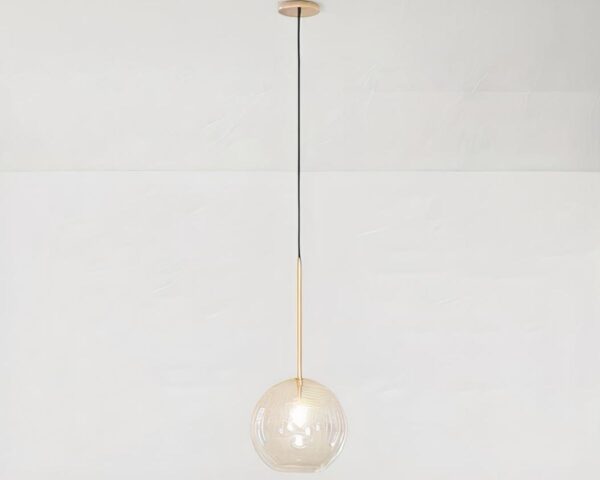 Suspension globe au design moderne et épuré en verre allumée sur fond gris.