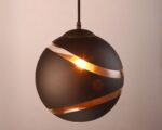 Suspension globe noire au design chic et élégant allumée sur fond gris.