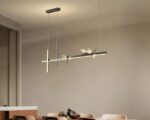 Suspension libellule silhouette élégante, de couleur noire, suspendue et allumée au-dessus d'une table de salle à manger.