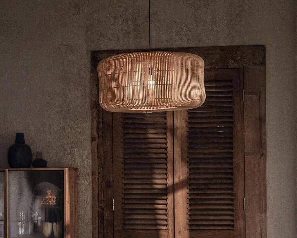 Suspension osier lumière tamisée, de forme ronde, de couleur beige, allumée et suspendue dans une pièce de vie.