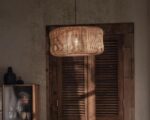 Suspension osier lumière tamisée, de forme ronde, de couleur beige, allumée et suspendue dans une pièce de vie.