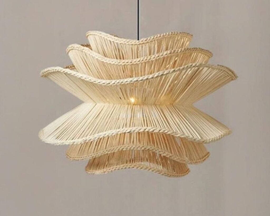 Suspension osier naturel ondulation douce, de couleur naturelle, suspendue et allumée. Fond beige foncé.
