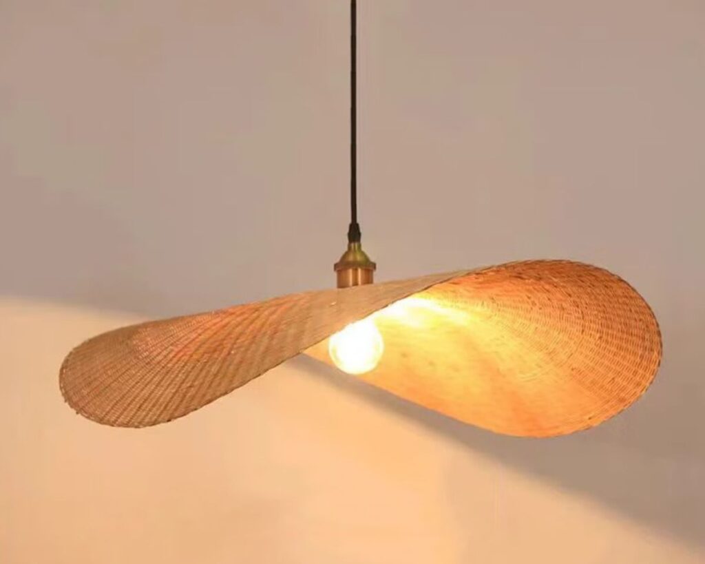 Suspension osier rétro chic base noire allumée sur fond beige.