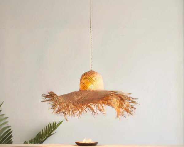 Suspension paille LED intemporelle et raffinée sur fond gris avec une plante verte en bas