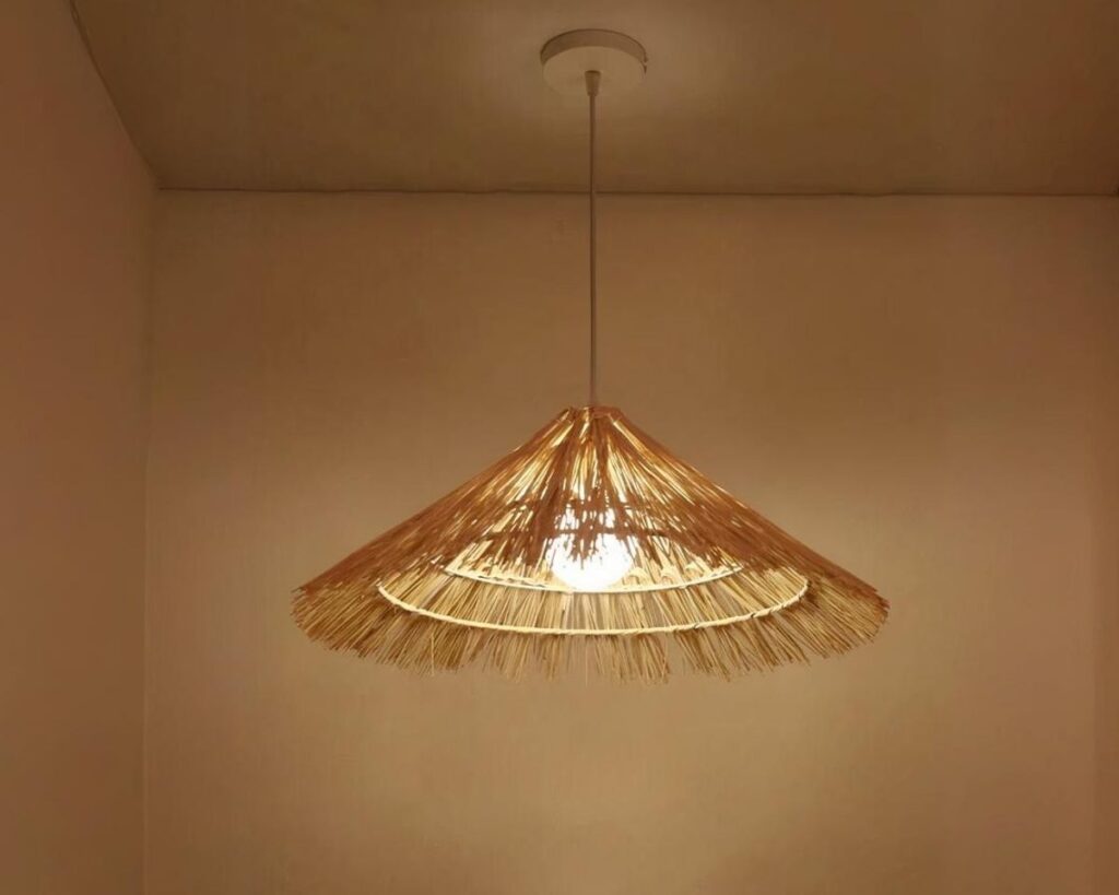Suspension paille LED tendance faite à la main sur fond marron.