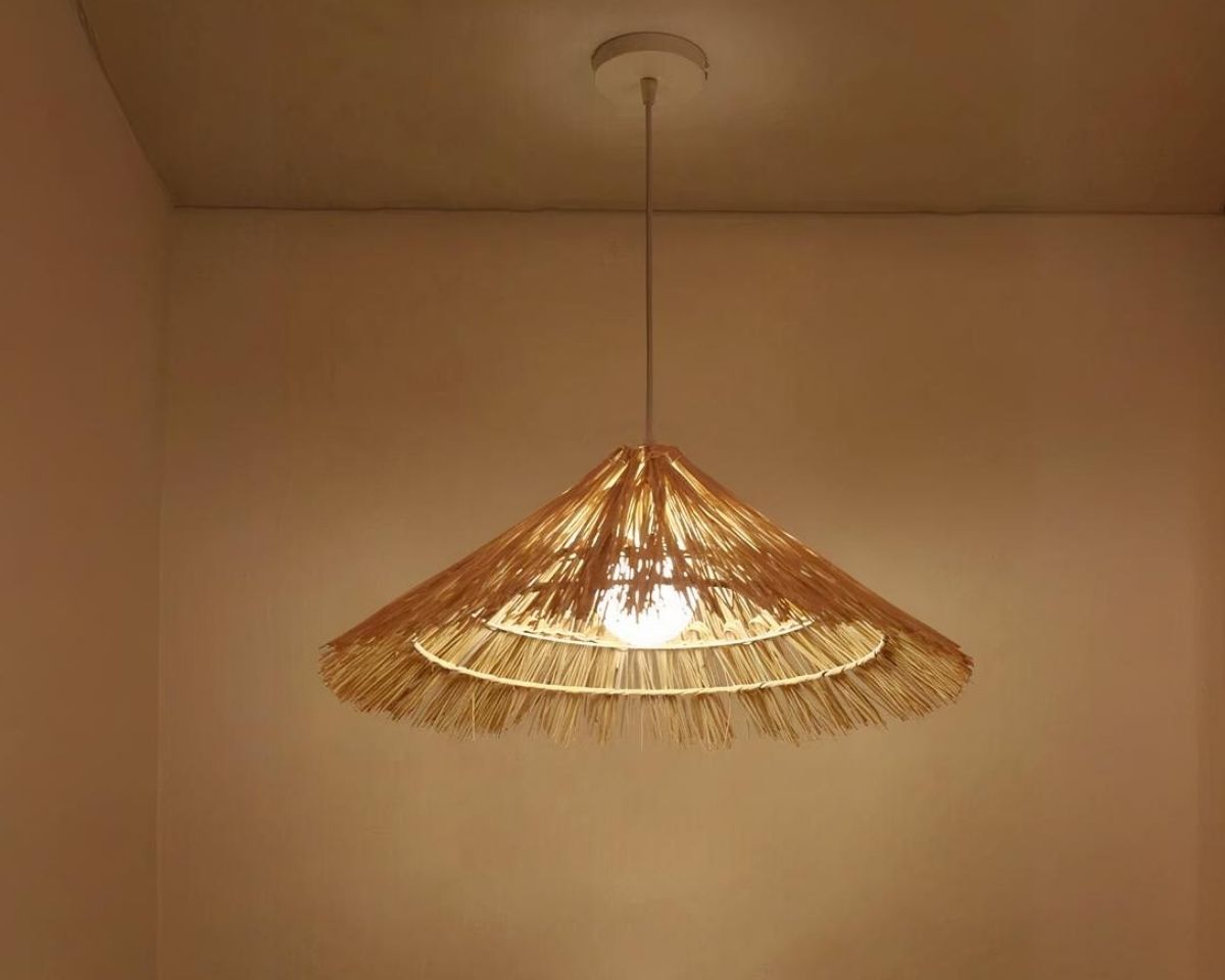 Suspension paille LED tendance faite à la main sur fond marron.