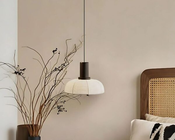 Suspension papier japonais décorative sur fond beige avec un lit sur la droite et une plante fine sur la gauche.