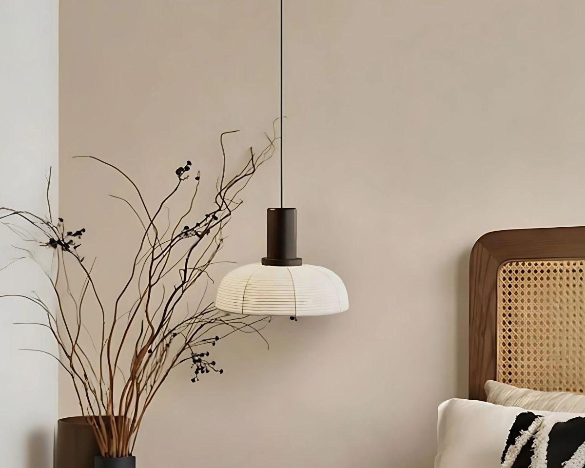 Suspension papier japonais décorative sur fond beige avec un lit sur la droite et une plante fine sur la gauche.
