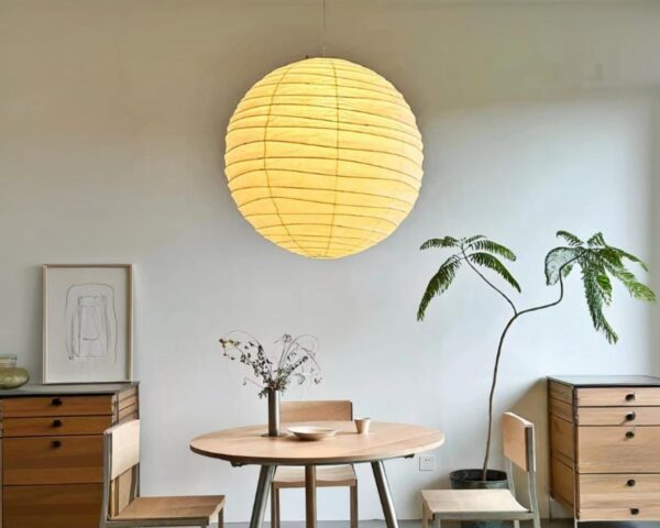 Suspension papier japonais en forme de sphère dans une pièce avec des meubles beige contre le mur de derrière et une table basse ronde au centre.
