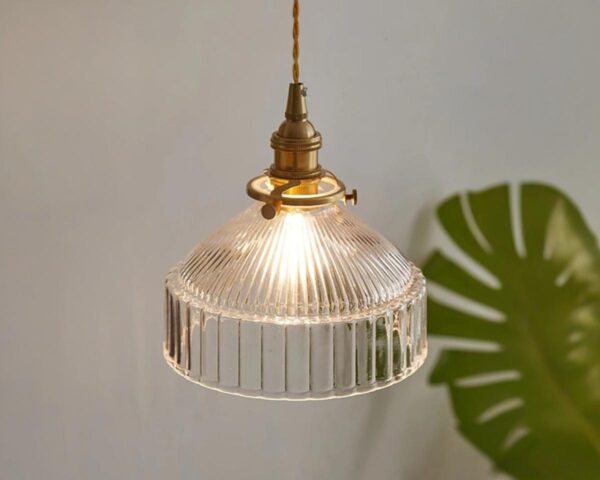Suspension rétro en verre coloré design élégant, de couleur transparente, avec une feuille verte à côté et un fond beige.