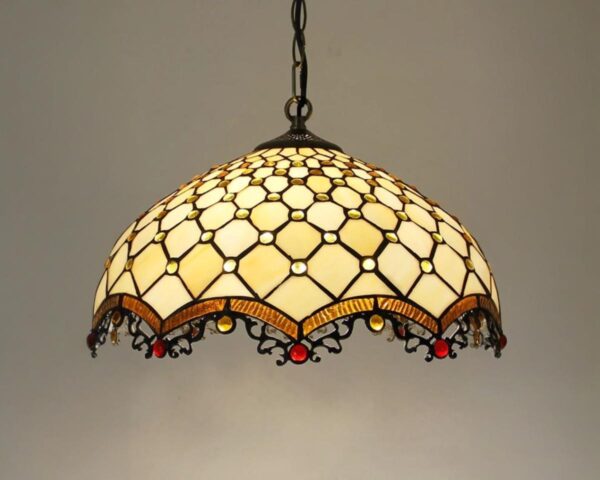 Suspension rétro vitrail baroque, de couleur jaune, allumée et suspendue. Fond beige.