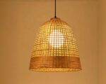 Suspension rotin en forme de cloche sur fond beige.
