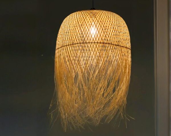 Suspension style raphia décoratif, installée dans une pièce sombre, avec une ampoule allumée.