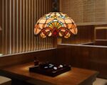 Suspension style Tiffany effet vitraux est installé au-dessus d'une table avec une ampoule allumée.