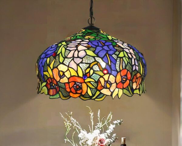 Suspension style Tiffany multicolore fleurie, avec une ampoule allumée, au-dessus d'un bouquet de fleur.