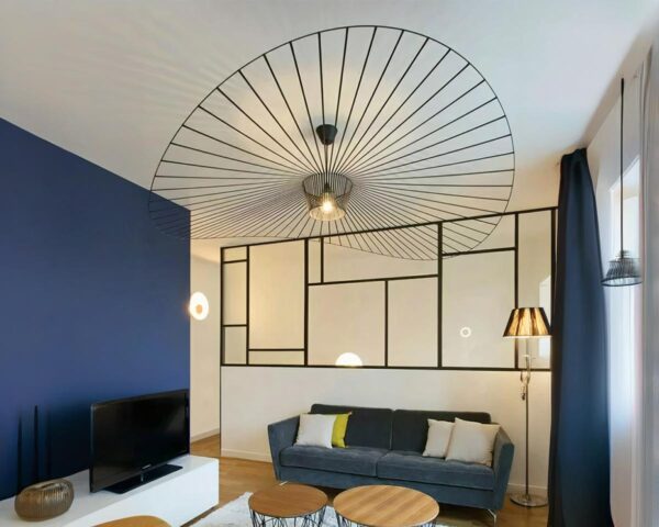 suspension style vertigo noire moderne, installée dans un salon moderne avec un mur bleu foncé et une verrière.