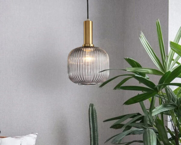 Suspension vintage originale et décorative en verre allumée dans une pièce à côté d'une plante