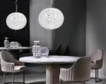 Suspension globe design et moderne au style nordique allumée dans une salle à manger au-dessus d'une table ronde.