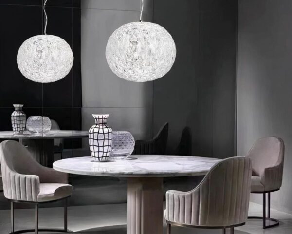 Suspension globe design et moderne au style nordique allumée dans une salle à manger au-dessus d'une table ronde.
