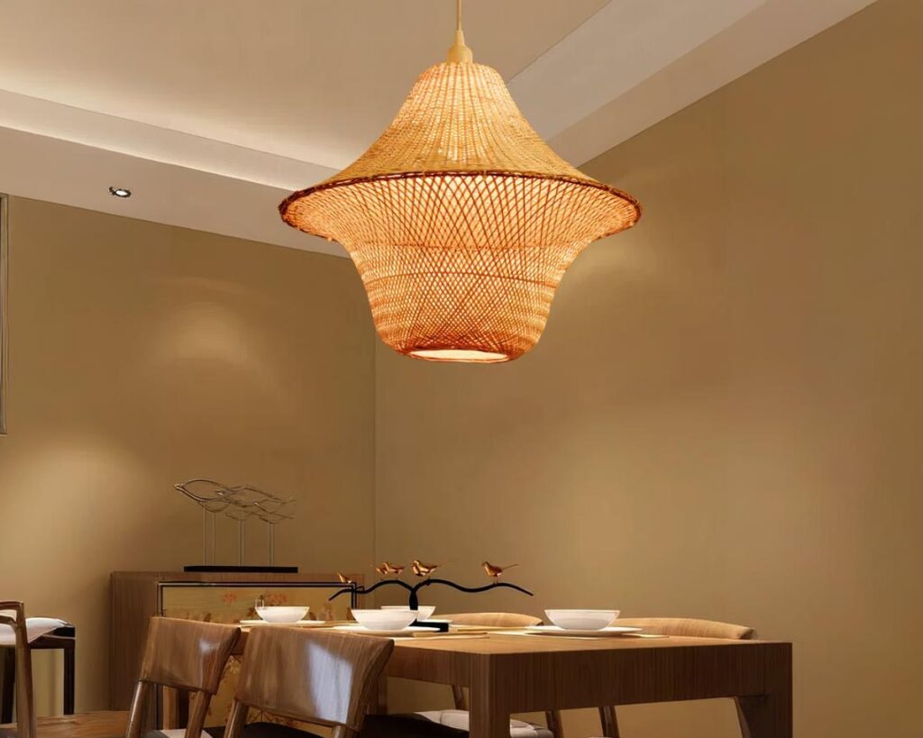 Suspension bambou originale et artisanale dans une pièce avec une grande table rectangulaire en bois et aux murs marron.