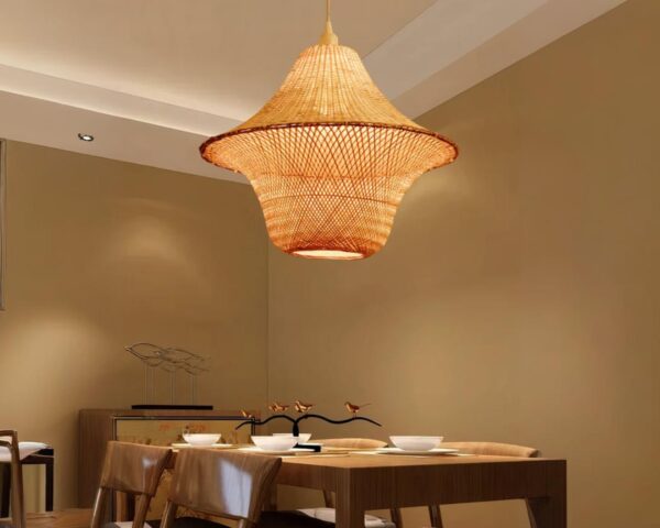 Suspension bambou originale et artisanale dans une pièce avec une grande table rectangulaire en bois et aux murs marron.