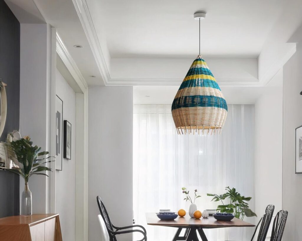 Suspension osier à rayures colorées dans une pièce avec une table et des chaises. Sur la gauche un meuble marron.