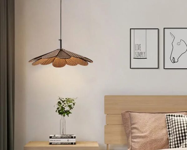 Suspension bambou en forme de pétale, allumée et suspendue au-dessus d'une table de chevet, dans une chambre à coucher.