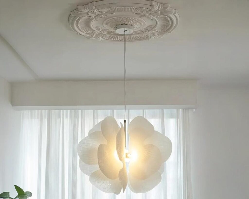 Suspension blanche en forme de papillon, allumée et suspendue dans une pièce de couleur claire.