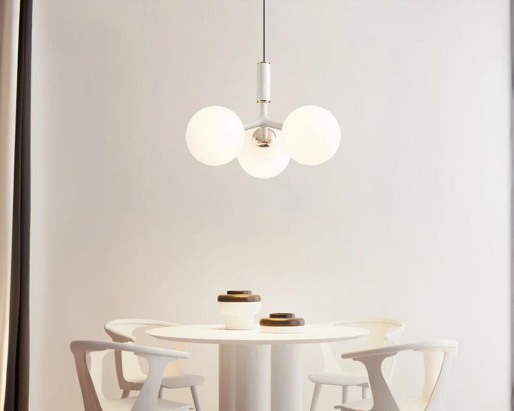 Suspension boule en verre chic, de couleur blanche, allumée et suspendue au-dessus d'une table de salle à manger. Fond beige clair.