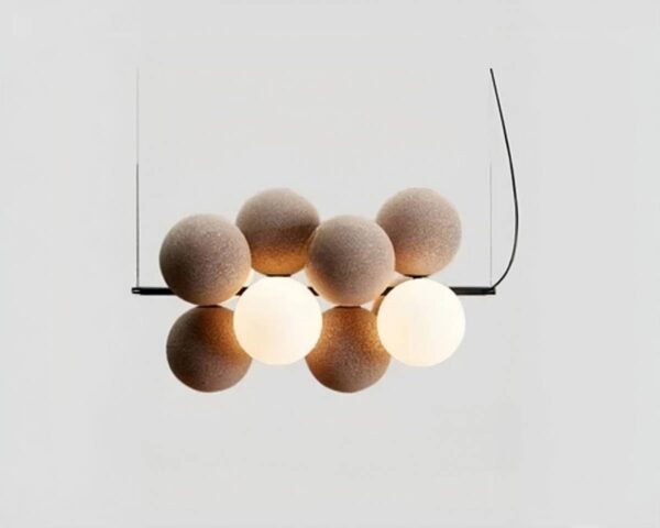 Suspension créative et nordique avec boules de couleur beige et deux boules allumée tenues sur une barre noire qui elle-même est suspendue par deux câbles noirs aux extrémités.