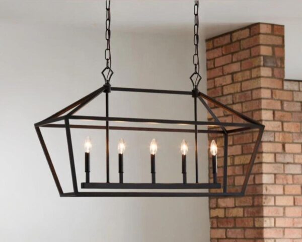 Suspension industrielle noire et rectangulaire, allumée et suspendue à côté d'un mur en brique.