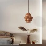 Suspension LED design sculptural, suspendue au-dessus d'une petite table de salon.