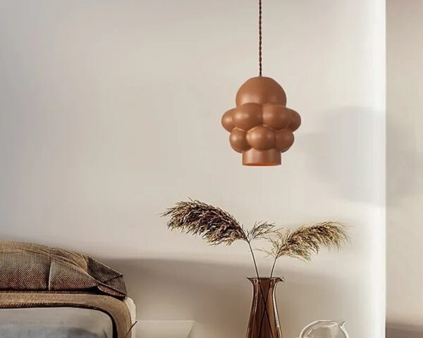 Suspension LED design sculptural, suspendue au-dessus d'une petite table de salon.
