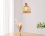 Suspension naturelle en forme de cloche, allumée et suspendue au-dessus d'une table avec un vase posé sur celle-ci.
