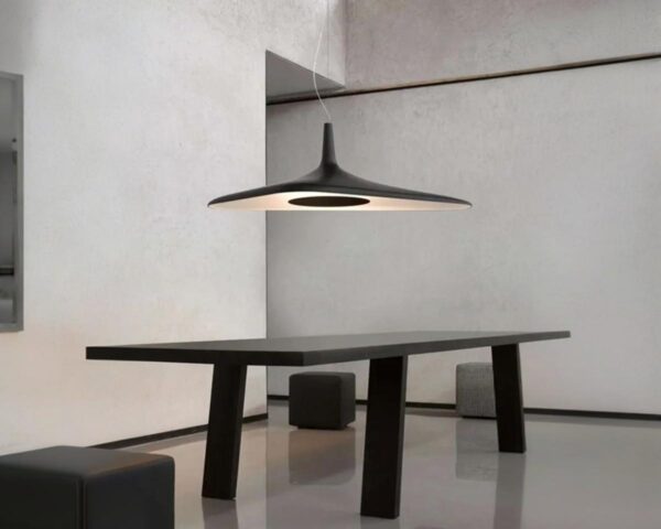 Suspension noire design futuriste, suspendue au-dessus d'une table noire et dans un décor minimaliste.