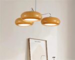 Suspension orange et décorative à trois têtes sur fond gris